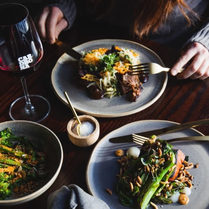 Elegant plated dinner with meat and greens, paired with red wine and gold cutlery at Cardrona.